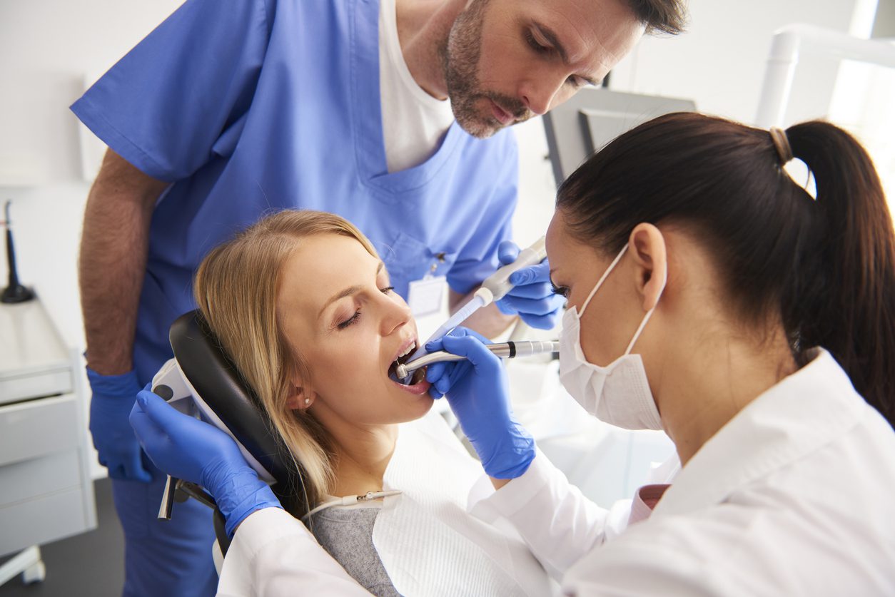 Dentist working on a woman's teeth with her assistant
