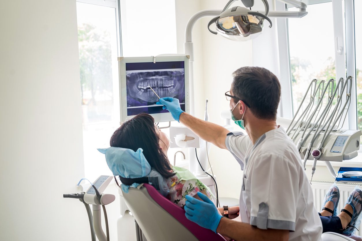 Doctor dentist showing patient's teeth on dental X-ray