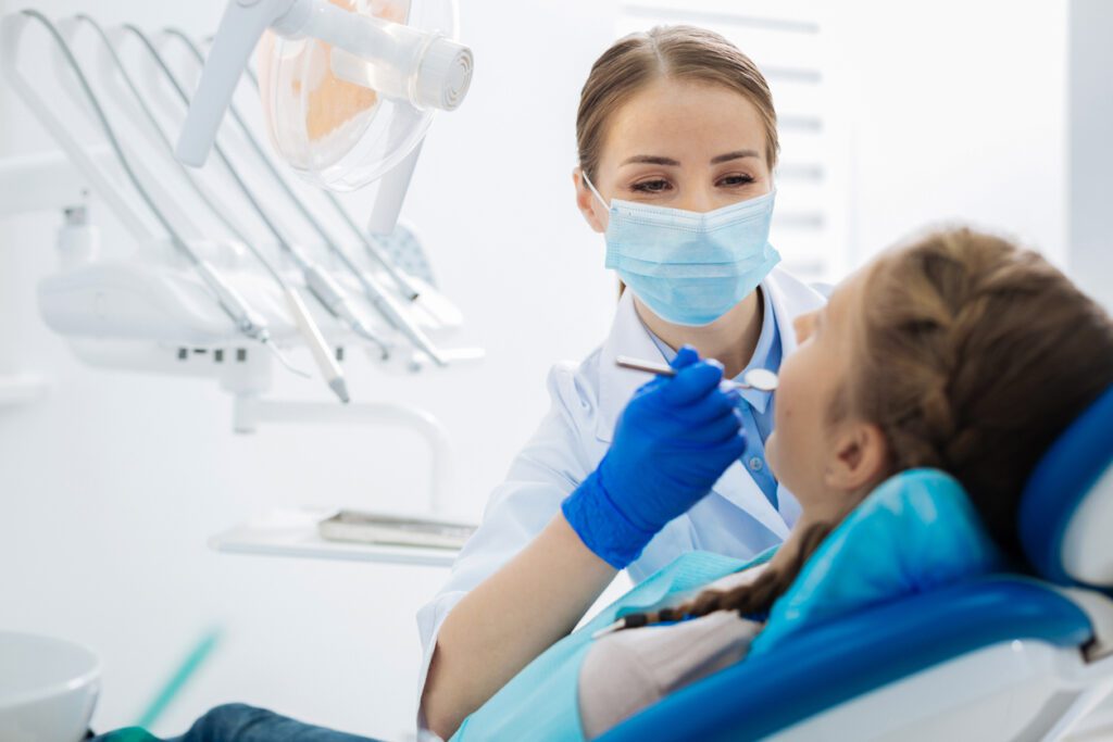 Female dentist looking at her patients teeth to determine if she has TMD.